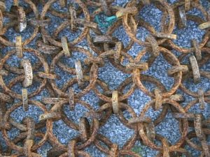 A close up of a scallop dredge bag made from steel rings on ground