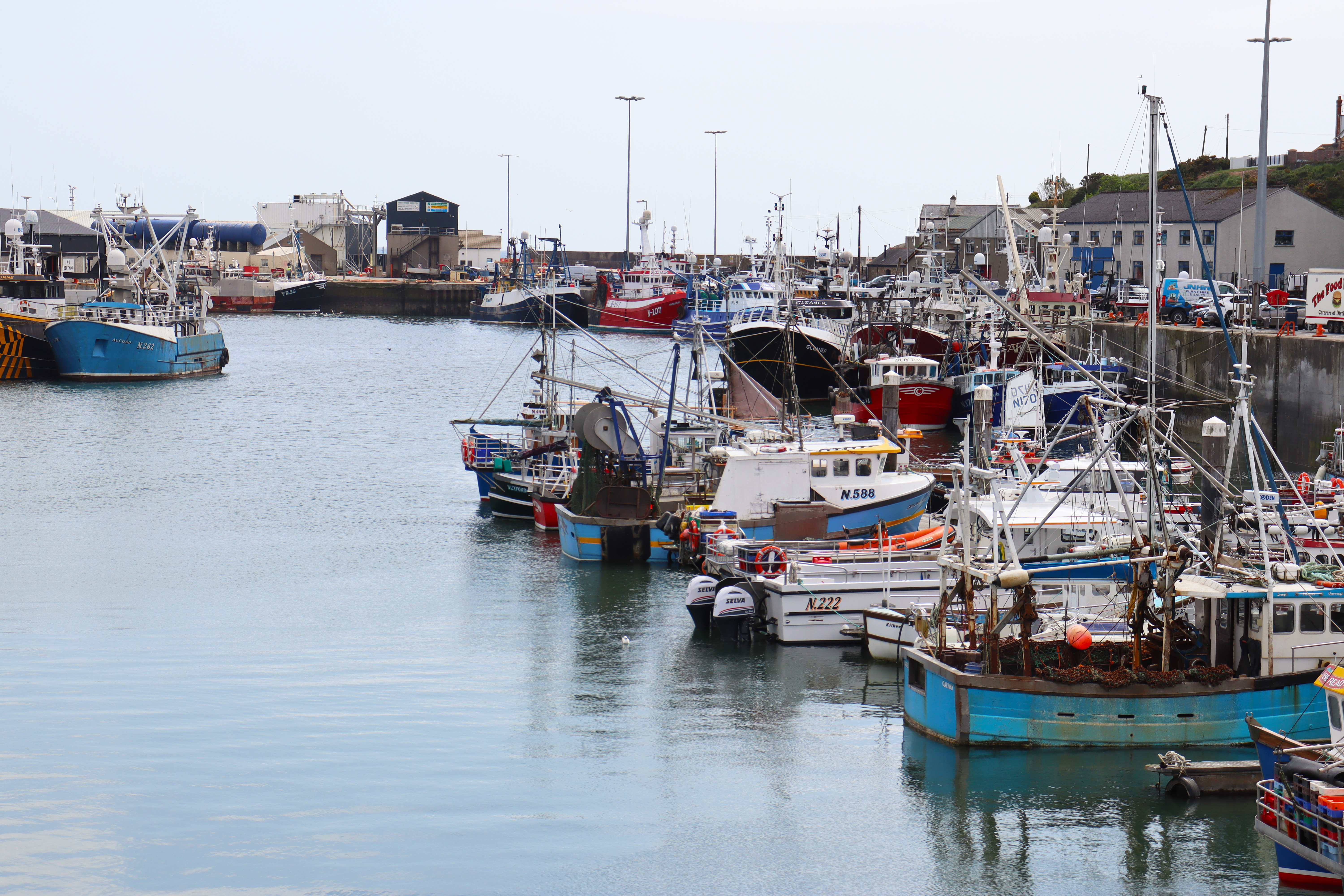 Several fishing boats docked in a quiet harbour.