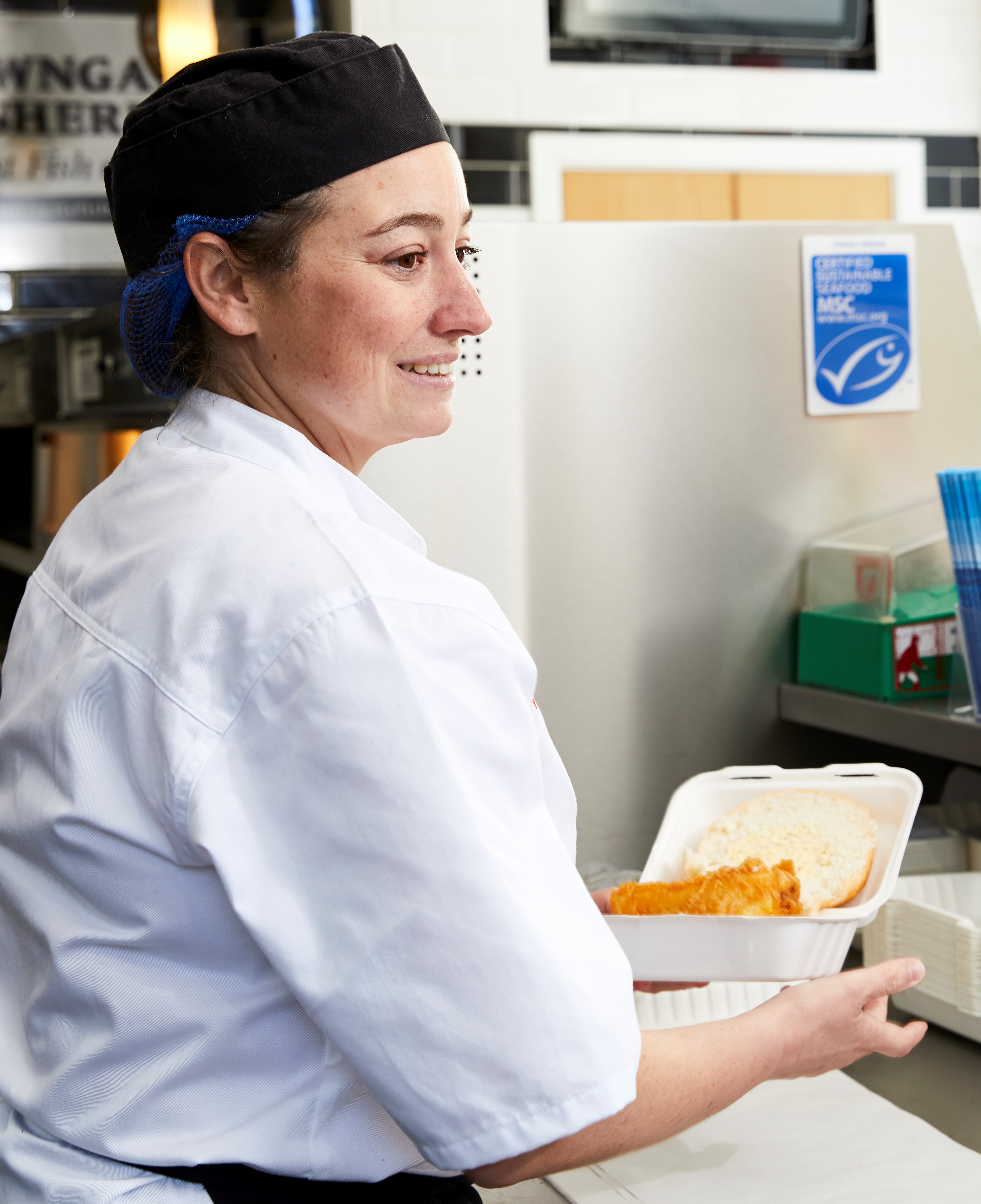 Chip shop worker serving fish and chips