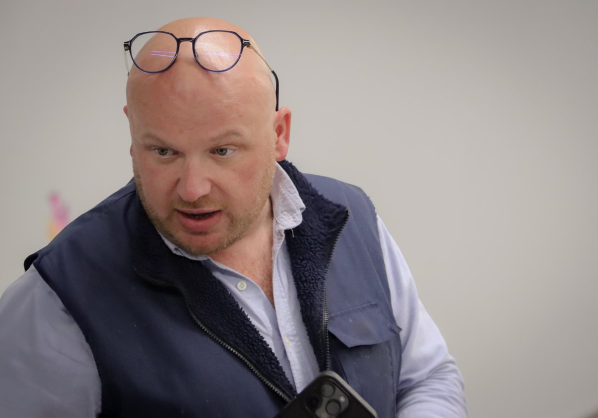 A man with glasses perched on his head focuses on something off camera.