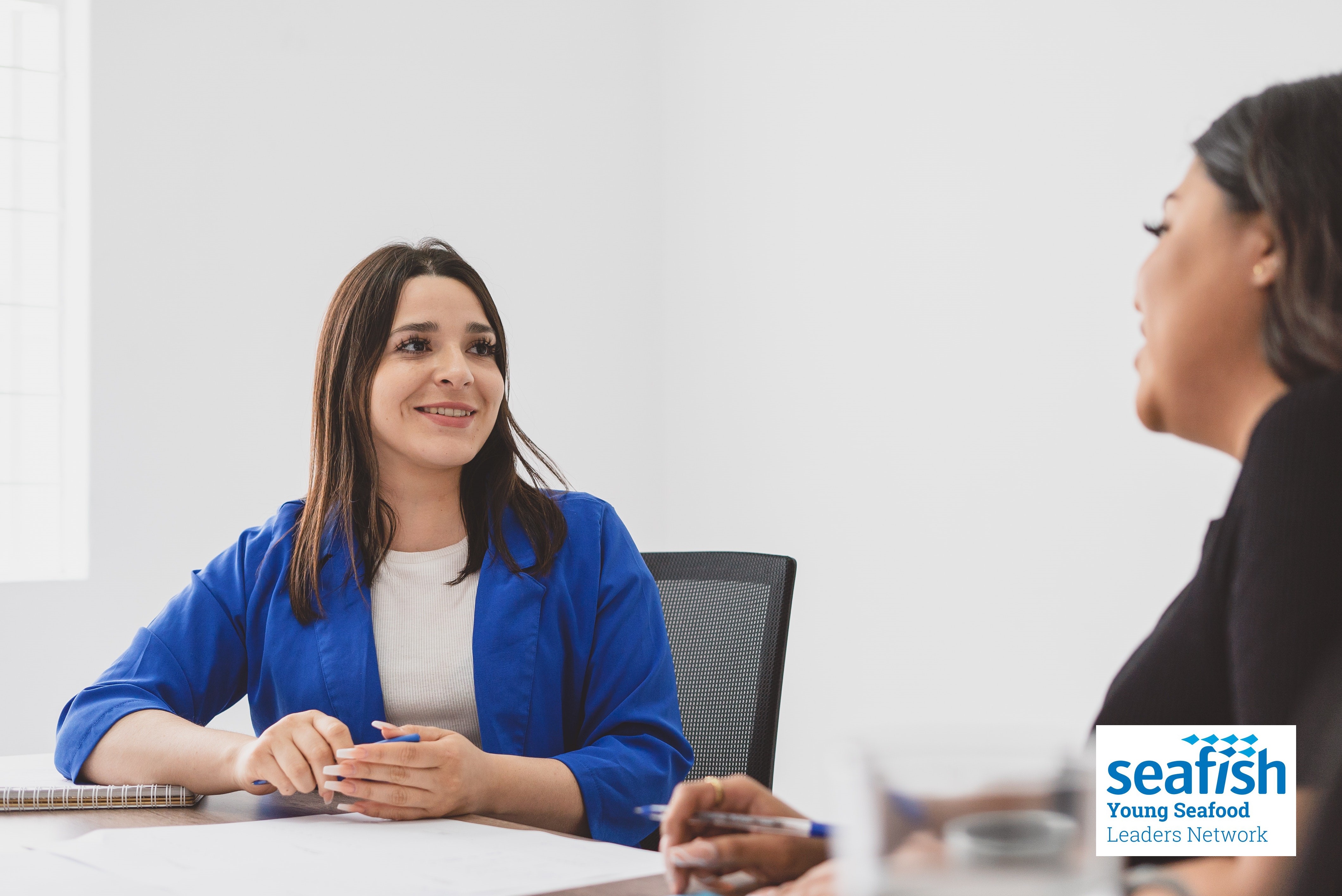 Photo of two women sitting next to each other talking.